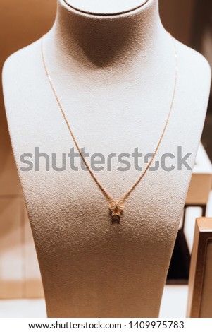 Jewelry mannequin stand with a gold, star shaped pendant with diamonds. 