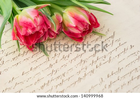 soft pink tulips with old handwritten love letter. sentimental vintage background with flowers and papers