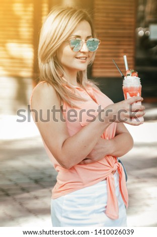 Beautiful woman in sunglasses with summer coctail has a fun outdoors.