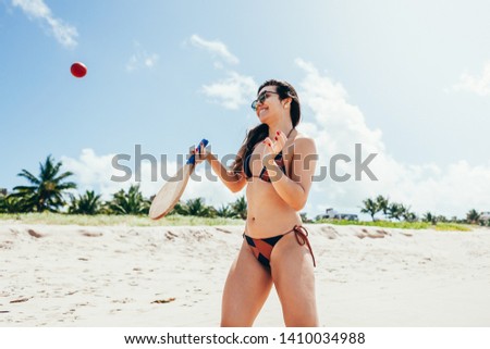 Beautiful woman in bikini having fun on the beach playing beach tennis