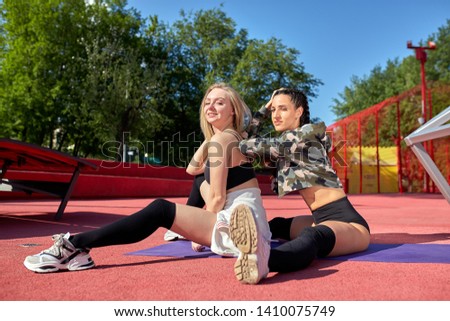 two girls Smiling and beautiful dressed in sportswear posing on the playground outside. Wellness concept. Calmness and relax, woman happiness.