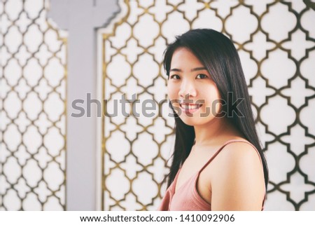 Vintage Photography style of pretty Asian woman at Indian or Moroccan pattern wall, outdoor portrait, selected focus.