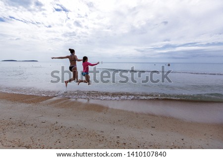Happy two little girls running on the beach early morning