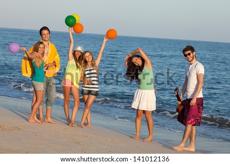 Young people enjoying a summer beach party, dancing. Young fun party people enjoying a summer party on the beach with guitar and balloons, dancing.