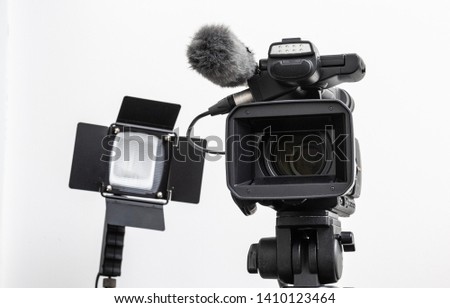 video camera on the tripod and spotlight harogen lamp isolated on white background, in concept of movie making equipment, TV production.