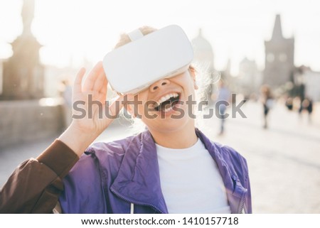 Woman wearing headset augmented virtual reality in history city center. Concept of virtual museum. Woman in headset wondering the new technology. Royalty-Free Stock Photo #1410157718