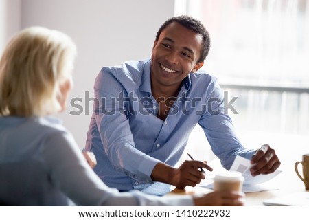 Smiling african american professional manager advisor designer talking with client listen to customer preferences at business meeting, diverse colleagues having conversation share design idea at work Royalty-Free Stock Photo #1410222932