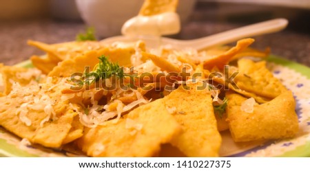 A plate full of mexican nachos with cheesy dip and cheese,herbs,coriander dressing.
Food background image.