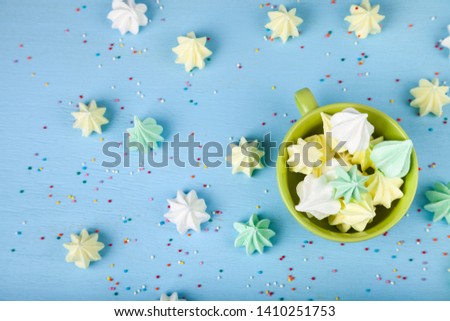 Meringue in a green cup on a blue  wooden background, top view. Delicious dessert. Colorful handmade meringue .