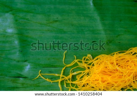 A picture of traditional Thai dessert, golden threads, on banana leaf.