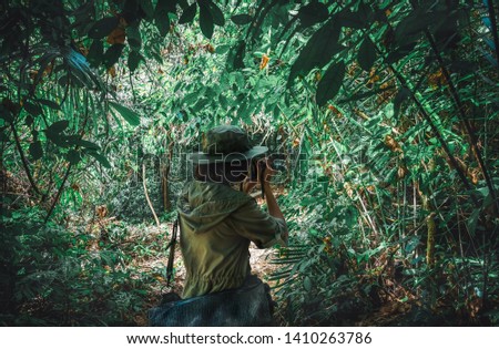 Outdoor lifestyle traveler or conservator woman taking photo in jungle deep rain forest, Adventure tourist travel Thailand summer holiday vacation, Tourism beautiful destinations place southeast Asia