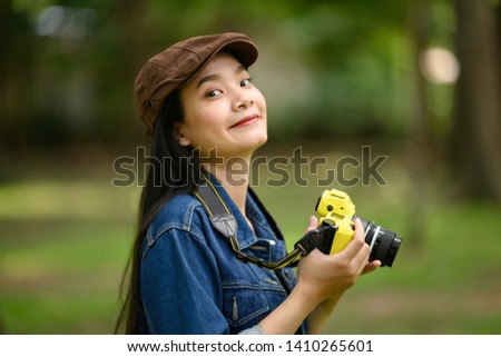 Portrait of beautiful young Asian woman with camera at summer green park