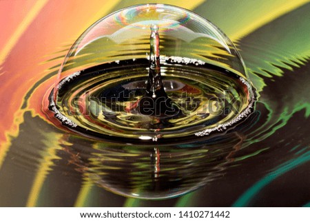 Photographs of water droplets photographed with the high speed photography method, with colorful backgrounds that are visible in the reflection in the water.