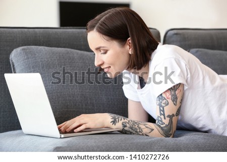 Beautiful tattooed woman working on laptop at home