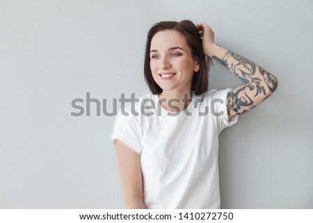 Stylish tattooed woman on light background