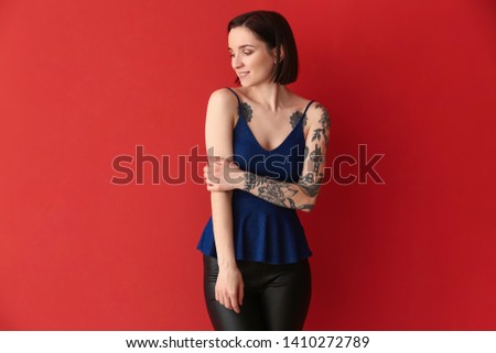 Beautiful tattooed woman on color background