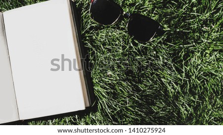 book (notebook) on the grass and sunglasses