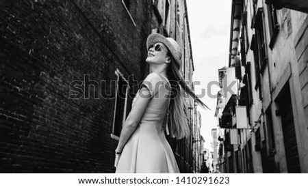 stylish girls in a dress and sunglasses looking at the building and smile on the street city on black and white photography