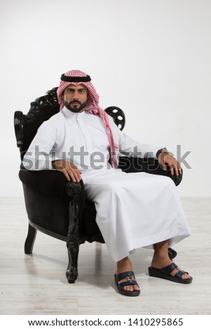 Portrait of an arab man sitting down on a chair. Royalty-Free Stock Photo #1410295865