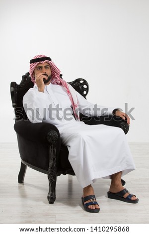 Portrait of an arab man sitting down on a chair. Royalty-Free Stock Photo #1410295868