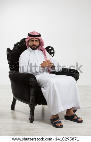 Portrait of an arab man sitting down on a chair. Royalty-Free Stock Photo #1410295871