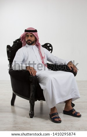 Portrait of an arab man sitting down on a chair. Royalty-Free Stock Photo #1410295874