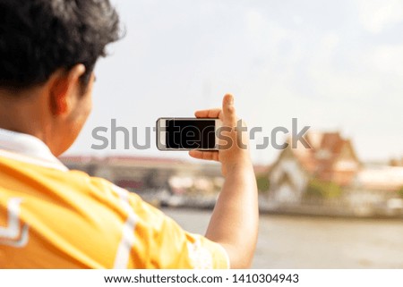 Hand holding smart phone taking photo of Buddhist temple