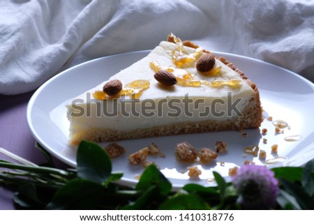 Classic cheesecake on a plate served with caramel and grated almonds. A piece of cheesecake on a plate on a white background decorated with almonds.