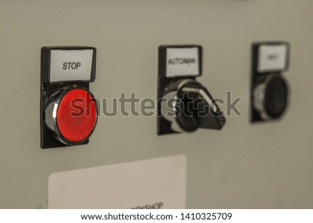 A Bright red stop button on an industrial machine working in a factory switches on a white background. Electrical devices for production and stop buttons for health and safety.