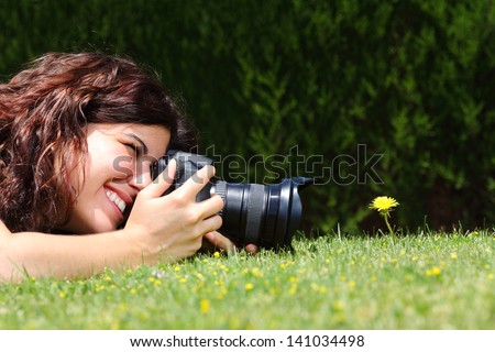 Profile of a beautiful woman taking a macro photography of a flower on the grass in a park