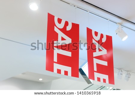 Close up of big red sale sign in Clothes shop during the long holiday with spotlight to illuminate the store. Special offer and deals are available.