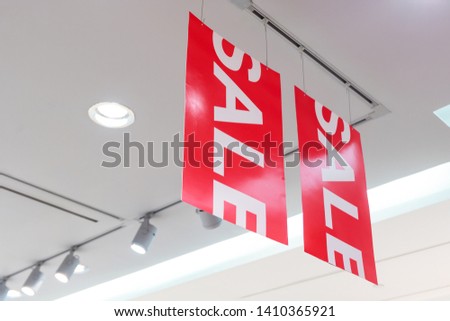Close up of big red sale sign in Clothes shop during the long holiday with spotlight to illuminate the store. Special offer and deals are available.