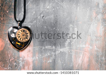 on the old ancient wall there is a pendant in the shape of a heart on a rope, and inside it is an old clock mechanism; concept photo show that there is always time for love
