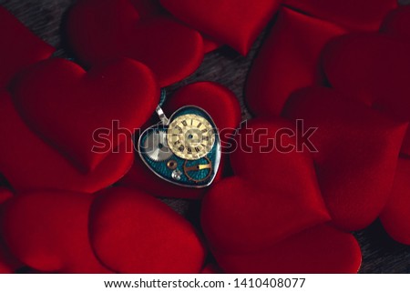 pendant in the form of a heart and the clockwork inside lies on the heart-shaped pads; idea for an image of time and love