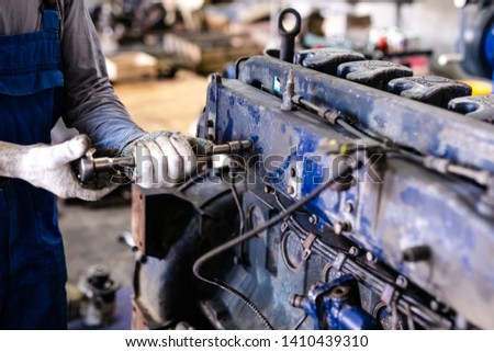 Mechanic repairs old motor of truck in a car repair station. Disassemble engine block vehicle. Motor capital repair. Car service concept.