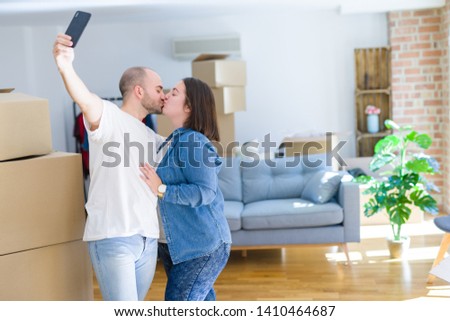 Young couple taking a picture photo using smartphone at new home, smiling happy for moving to new apartment