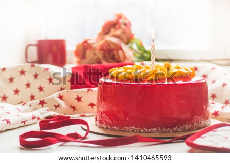 Birthday cake with one candle and red frosting. Round cake with mango.