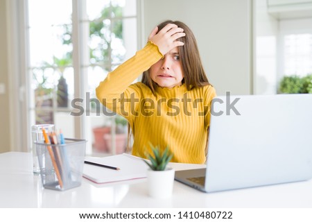 Beautiful young girl studying for school using computer laptop stressed with hand on head, shocked with shame and surprise face, angry and frustrated. Fear and upset for mistake. Royalty-Free Stock Photo #1410480722