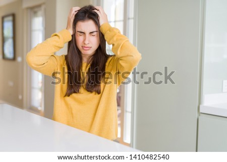 Beautiful young woman wearing yellow sweater suffering from headache desperate and stressed because pain and migraine. Hands on head.
