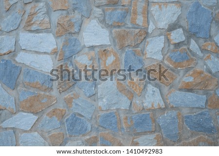 Pattern of irregular blue and brown stones on a textured wall background