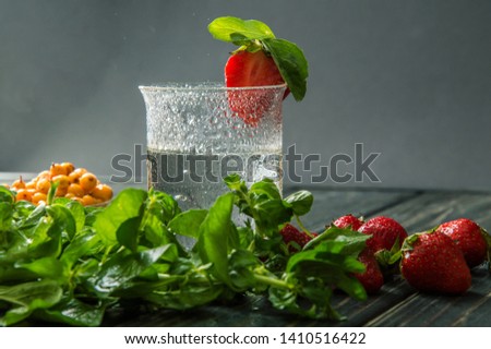 Close up, macro. Preparation of the drink. A glass of water, mint, strawberry. Grey background. Copy space.