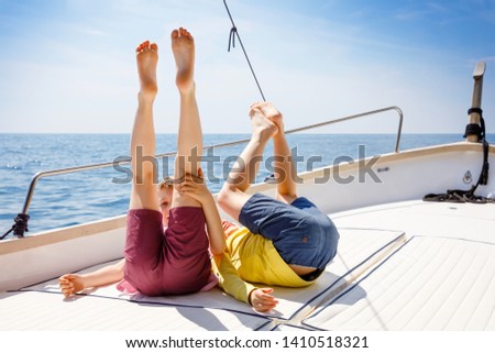 Two little kid boys, best friends enjoying sailing boat trip. Family vacations on ocean or sea on sunny day. Children smiling. Brothers, schoolchilden, siblings having fun on yacht.
