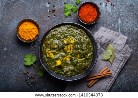 Palak paneer, traditional vegetarian Indian dish with cheese paneer, pureed spinach and spices. Indian green paneer curry in rustic ceramic bowl on concrete background, top view  Royalty-Free Stock Photo #1410544373