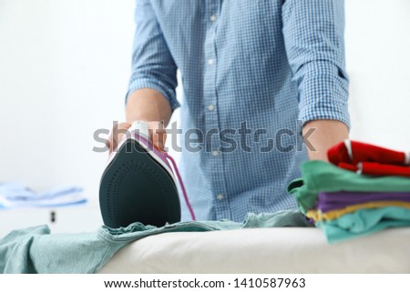 Man ironing clothes on board at home, closeup