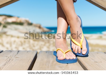 Low section of woman wearing slippers while standing on board walk Royalty-Free Stock Photo #141061453
