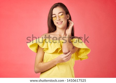 Cheerful pretty woman in a yellow dress coral background smile glasses fun model