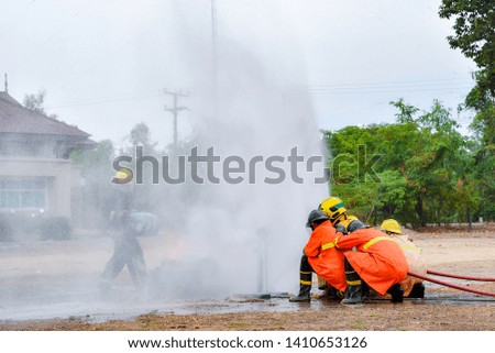Firefighters training using fire hose and control fire with water