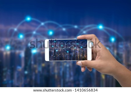 hand holding a smartphone and viewing a cityscape wifi technology , the user is searching places using an 
application.Internet Concept of global business