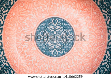 Beautiful authentic ornate floral pattern of pink, blue and white color plate. Round focused. Flat lay style. Cropped frame.
