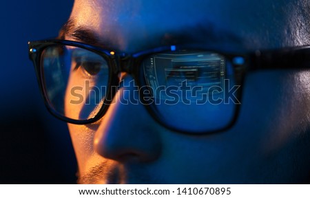vision, hacking and technology concept - close up of hacker eyes in glasses looking at computer screen in darkness Royalty-Free Stock Photo #1410670895